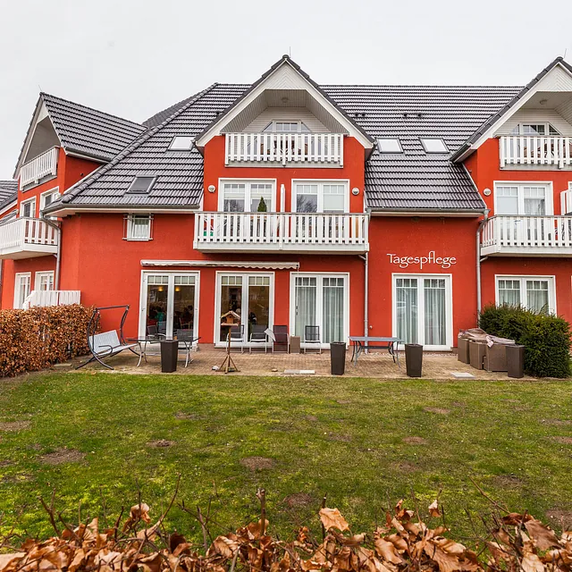 Rotes Reihenhaus mit weißen Balkonen und einer Terrasse der Tagespflege in Warnemünde